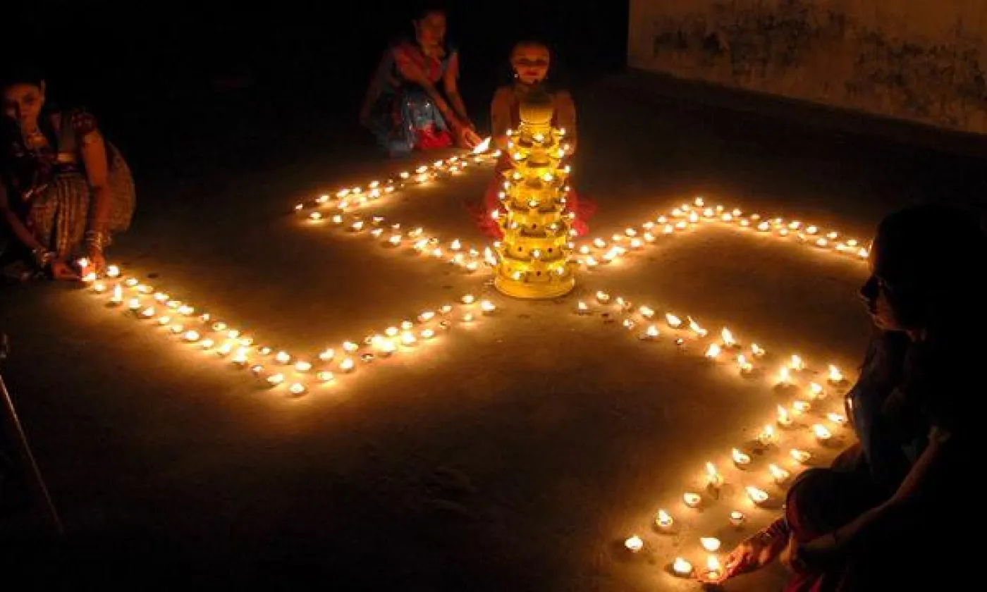 Une jeune femme formant une svastika avec des bougies lors d'un festival hindou, le 8 novembre 2007, en Inde. KEYSTONE - STR