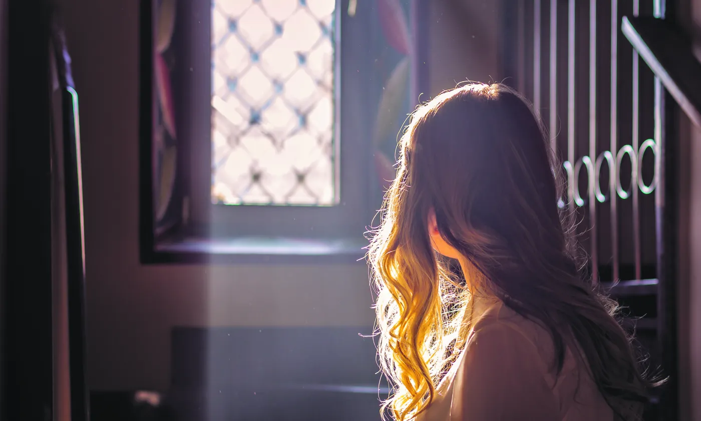 Jeune adolescente regardant par la vitre d'une église. © iStock